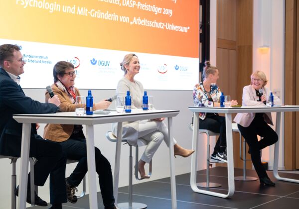 Bühne mit vier Protagonisten für die Podiumsdiskussion beim "Dialog Zukunft Arbeitsschutz 2025"